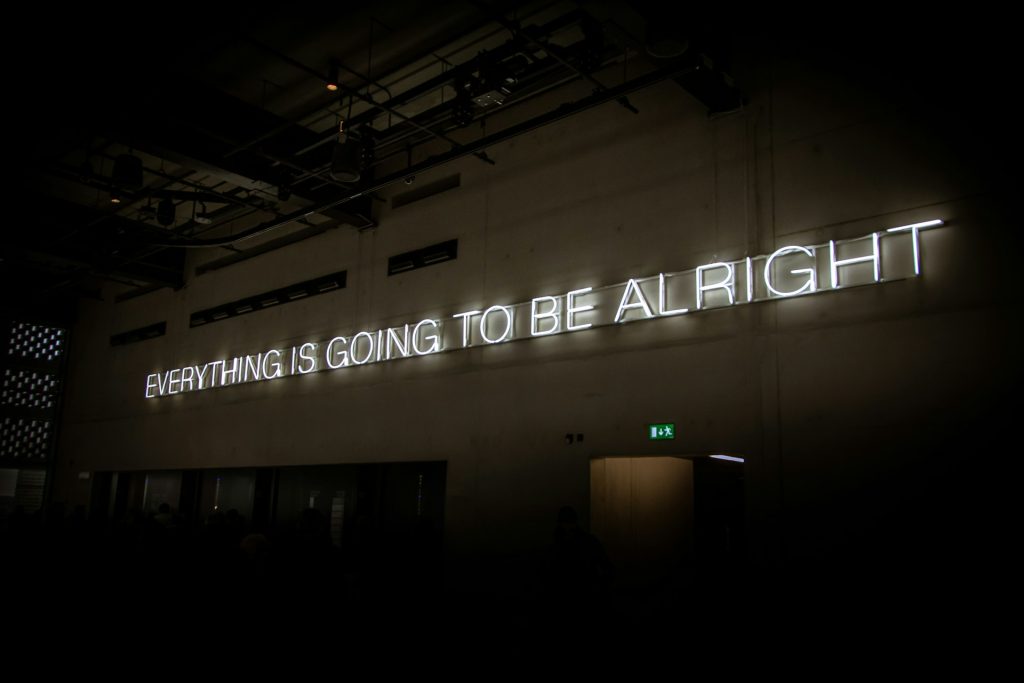 White neon lights in capital letters spell "Everything is going to be alright"